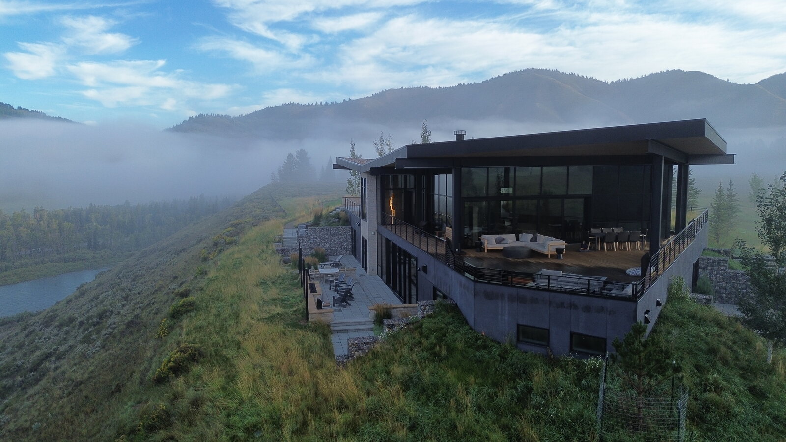 Aerial photo of a luxury mountain home above a fog-filled river valley