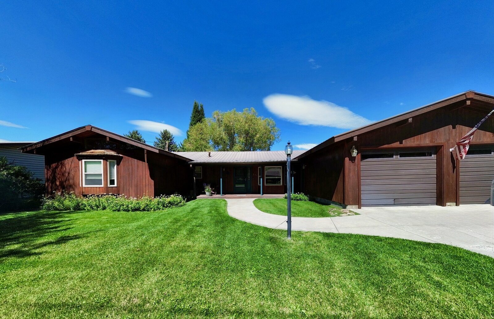 Aerial real estate photo of a ranch home with driveway and mountain backdrop